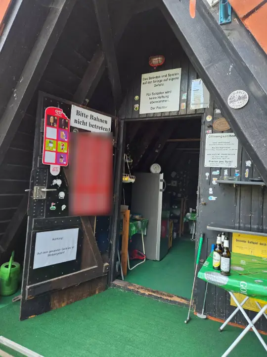Eingang der Holzhütte mit Eiskarte, Hinweisschildern und Getränken
